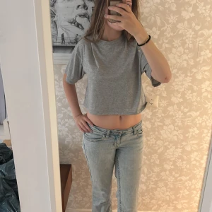 Grå glittrig croppad t-shirt från Kappahl - Säljer en enkel och stilren grå glittrig croppad t-shirt från Kappahl. T-shirten har korta ärmar, rund halsringning och är tillverkad i ett mjukt bomullsmaterial. Perfekt till jeans eller kjol för en avslappnad look.