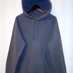 Mörkgrå hoodie från Bik Bok, storlek M - En basic mörkgrå hoodie från Bik Bok i storlek M. Tröjan har huva med snörning, känguruficka och långa ärmar. Tillverkad i en mjuk blandning av polyester och bomull, perfekt för chill dagar eller när du vill ha en enkel och stilren look. Kan skickas med extra pris via post. 