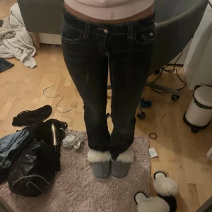 Svarta jeans med vita sömmar - Snygga svarta jeans med kontrasterande vita sömmar och dekorativa fickor bak. Byxorna har en klassisk femficksdesign och en bootcut-stil som ger en tidlös look.