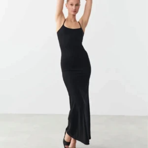 Svart långklänning med smala axelband - Elegant svart långklänning med smala axelband och figurnära passform. Perfekt för en stilren look.