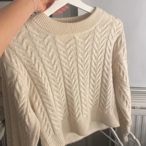 Beige stickad tröja från Vero Moda - Säljer en mysig beige stickad tröja från Vero Moda. Tröjan har ett snyggt flätmönster och långa ärmar.