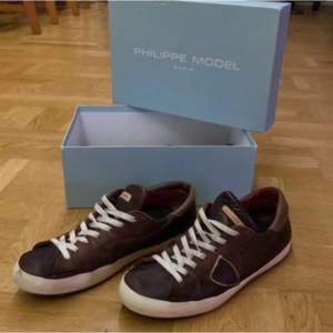 Snygga bruna sneakers från Philippe Model med vita snören och en stilren design. Skorna har en klassisk look med en vit sula och är perfekta för en avslappnad stil.