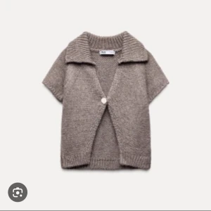 Brun stickad kofta från Zara - Mysig brun stickad kofta från Zara med korta ärmar och en enkel knapp framtill. Perfekt för lager-på-lager under kyliga dagar. Den har en bred krage som ger en avslappnad look.