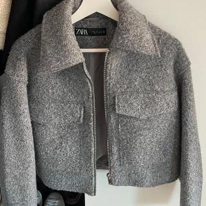 Grå ulljacka från Zara - Snygg grå ulljacka från Zara med en croppad passform. Endast använd ett fåtal gånger så är i mycket fint skick.