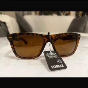 Solglasögon från Bliz - Snygga solglasögon från Bliz med en klassisk wayfarer-design. Bågarna har ett coolt leopardmönster och bruna polariserade linser för att minska bländning. Perfekta för soliga dagar och ger en stilren look.