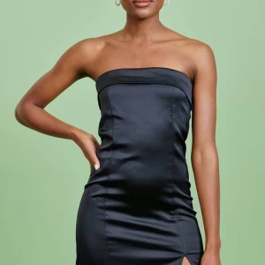 Svart satin tubklänning - Snygg svart axelbandslös satinklänning i polyester med en elegant slits framtill. Perfekt för en kväll ute eller en speciell tillställning. Klänningen har en tight passform som framhäver figuren. Använd eventuellt en gång, men bara hängt i garderoben annars. Hund finns i hemmet.
