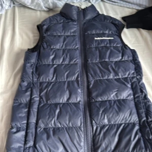 Mörkblå dunväst från Peak Performance - Säljer en snygg mörkblå dunväst från Peak Performance. Västen har en dragkedja framtill och är perfekt för kyligare dagar. Den är quiltad och ger ett stilrent intryck. Passar bra för både vardag och utomhusaktiviteter. Inga defekter!