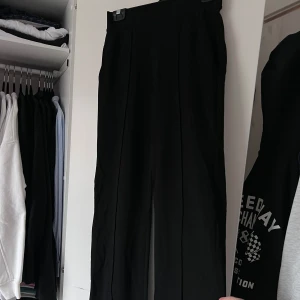 Svarta kostymbyxor (Använda 1 gång) - Snygga svarta kostymbyxor med hög midja och raka ben. Byxorna har en stilren design med diskreta fickor baktill. Perfekta för en elegant look. Önskar du veta exakta mått? Tveka inte att höra av dig!