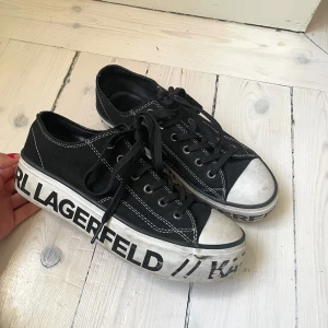 Svarta sneakers från Karl Lagerfeld - Unika svarta sneakers med vit sula och tydlig Karl Lagerfeld-logga. Skorna har snörning och vita detaljer vid tån. Limited edition!