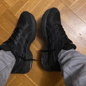  Asics skor - Säljer ett par svarta sneakers från Asics. Skorna har en sportig design med snörning och är tillverkade i syntetmaterial. Perfekta för träning eller vardagsbruk. Jag har glömt vilken modell de är