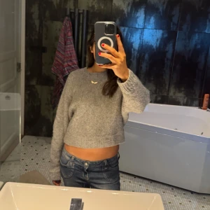 Grå croppad stickad tröja - Säljer en mysig grå croppad stickad tröja med långa ärmar. Perfekt för en avslappnad stil och passar bra med jeans och kjol.💕