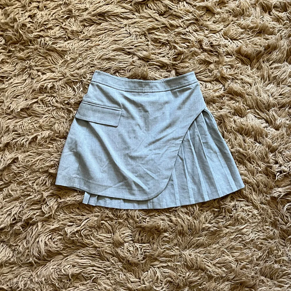 Grå kjol med plisserade detaljer, i fint skick. Står att det är storlek M, men skulle säga att det är en S.. Hameet.
