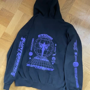 Svart  zip hoodie med lila tryck - Den passar som typ M. Perfekt för en avslappnad stil.