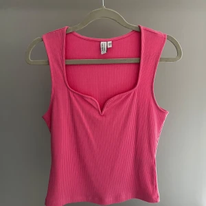 Rosa ribbad linnetopp från Other Stories - Säljer en snygg rosa ribbad linnetopp från Other Stories. Toppen har en unik v-ringad design och är ärmlös, perfekt för varma dagar. Tillverkad i ett mjukt och bekvämt material.