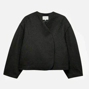 Svart jacka från Stockh LM Studio - Snygg svart jacka från Stockh LM Studio i minimalistisk design. Jackan har en omlottstil och är långärmad, perfekt för en stilren look. Den är gjord i ett mjukt material som ger en bekväm passform.