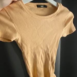 Ribbad tröja  - Tajt ribbad tröja från bikbok. Storlek XS. Jätte Stretchigt tyg. Färgen är mer åt det aprikosa hållet men gör sig inte riktigt rätt på bilderna. 