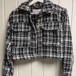 Svartvit rutig jacka från Amisu - Snygg svartvit rutig jacka från Amisu med croppad passform och knappar framtill. Jackan har långa ärmar och två fickor på bröstet.🤍