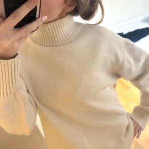 Beige stickad polotröja - Säljer en mysig beige stickad polotröja med ribbade detaljer vid krage och ärmslut. Har skit nertill. Perfekt för kyliga dagar och ger en stilren look. Passar bra till både jeans och kjol.