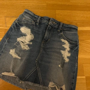 Blå jeanskjol från Hollister - Snygg blå jeanskjol från Hollister med slitna detaljer. Väldigt fint skick.