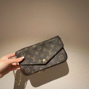 Mönstrad axelväska med kedja - Snygg axelväska med ikoniskt mönster och guldfärgad kedja. Perfekt för att ge din outfit en lyxig touch. Väskan har en praktisk storlek och en stilren design.