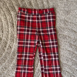 röda rutiga byxor - H&M (134) - Snygga röda byxor med klassiskt rutigt mönster från H&M. Perfekta för en trendig look med en bekväm passform. Tillverkade i mjukt material som ger en skön känsla hela dagen.
