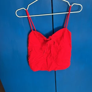 Röd linnetopp från J. Galt - Snygg röd linnetopp från J. Galt i 100% bomull. Toppen har smala axelband och en söt knytdetalj framtill. Aldrig använt. Perfekt för varma sommardagar!☀️❤️