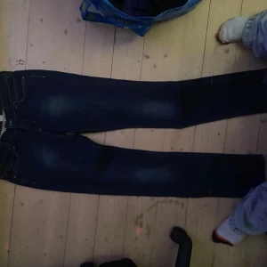 Mörkblå jeans från N&SON - Snygga mörkblå jeans från N&SON med klassisk femficksdesign och läderdetalj vid midjan. Perfekta för en avslappnad stil.