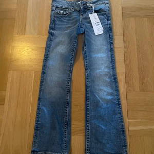 Blå jeans med bootcut - Snygga blå jeans med bootcut och klassisk femficksdesign. De har en knappdetalj på bakfickan och en lätt tvättad look. Perfekta för en avslappnad stil. De e helt nya och alltså aldrig använda köpta för 360kr