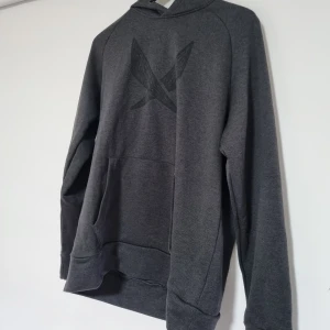 Mörkgrå hoodie Soc - Säljer en stilren mörkgrå hoodie med ett diskret tryck på framsidan. Tröjan har en klassisk design med långa ärmar och en praktisk magficka. Perfekt för en avslappnad look.