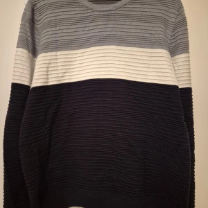 Randig tröja i grå, vit och svart - Säljer en stilren randig tröja i grå, vit och svart. Tröjan har en rund halsringning och långa ärmar. Perfekt för en avslappnad look.