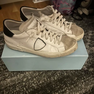 Vita sneakers från Philippe Model - Snygga vita sneakers från Philippe Model med grå detaljer och svart häl. Skorna har en klassisk snörning och är tillverkade i skinn. Nypris runt 3500kr mitt pris 1499kr. Om du har frågor så e det bara att höra av sig. Priset är ej hugget i sten så kom med förslag 