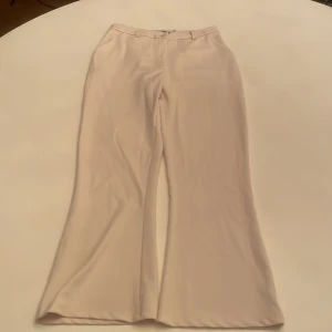 Beige vida byxor från 157 - Super snygga vit/beige kostym byxor från Lager 157 med en vid passform. Byxorna har en låg midja och är perfekta för en stilren look. De är tillverkade i ett mjukt material som ger en bekväm känsla hela dagen. Byxorna är helt oanvända och är i nytt skick😊