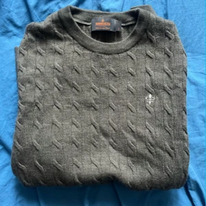 Grå kabelstickad tröja från Morris - Säljer en stilren grå kabelstickad tröja från Morris i 100% merinoull. Tröjan har en diskret logga på bröstet och rund halsringning. Storlek S men krympt lite så skulle säga xs är den riktiga storleken knappt andvänd.