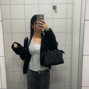 Grå omlottopp med knytband - Säljer en stilren grå omlottopp med knytband i midjan. Toppen är i nyskick och ser helt ny ut