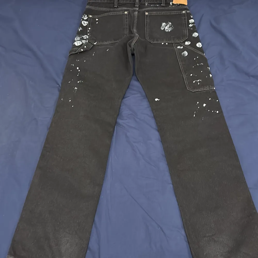 Coola svarta jeansbyxor från Weekday med unikt stänkmönster i vitt. Byxorna har en klassisk femficksdesign och raka ben. Perfekta för en avslappnad och trendig stil.. Farkut & Housut.
