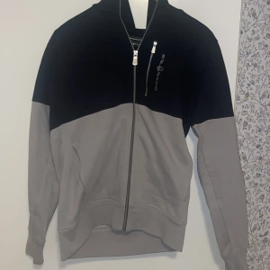 Svart och grå tröja från Sail Racing - Snygg svart och grå tröja från Sail Racing med dragkedja och en bröstficka med dragkedja. Modellen är Sail Racing Bowman och är köpt för Ca 1400. Tröjan är använd ett fåtal gånger och har inga som helst defekter. Skriv vid minsta fundering! 