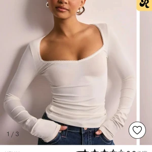 Vit långärmad topp - Säljer en stilren vit långärmad topp med en vacker U-ringad design. Toppen har en tight passform och är perfekt för att skapa en elegant look. Den är tillverkad i ett mjukt och bekvämt material. Inga defekter och använd ca 2 gånger.