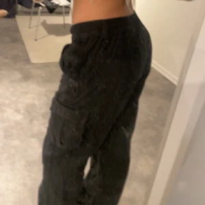 Svarta cargobyxor - Säljer ett par svarta cargobyxor med flera fickor och en loose passform. Byxorna har en bekväm midja och är perfekta för en avslappnad stil. De är tillverkade i ett slitstarkt material som passar bra för vardagsbruk.