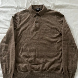Brun merinoullströja från Hugo Boss - Säljer en stilren brun tröja från Hugo Boss i extrafin merinoull. Tröjan har en klassisk pikékrage med tre knappar och ribbade muddar vid ärmslut och nederkant. Perfekt för en elegant och bekväm look. Den är i M men väldigt liten i storleken så den sitter som en S. Den är i fint skick