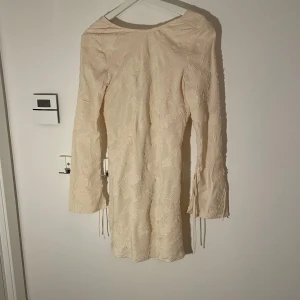 Krämvit klänning från H&M - Säljer en elegant krämvit klänning från HM. Den har en öppen rygg med snören man kan knyta . Är perfekt nu till sommaren! Skriv privat om bilder på!