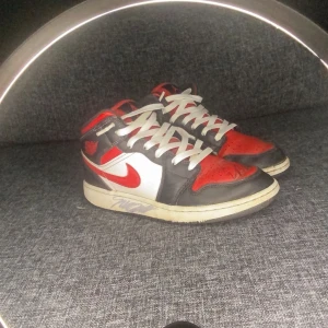Nike Air Jordans i rött och svart( signerade av mr savage) - Snygga Nike Air Jordans med en klassisk färgkombination av rött, svart och vitt. Skorna har snörning och en ikonisk design som passar perfekt för sneakerälskare.