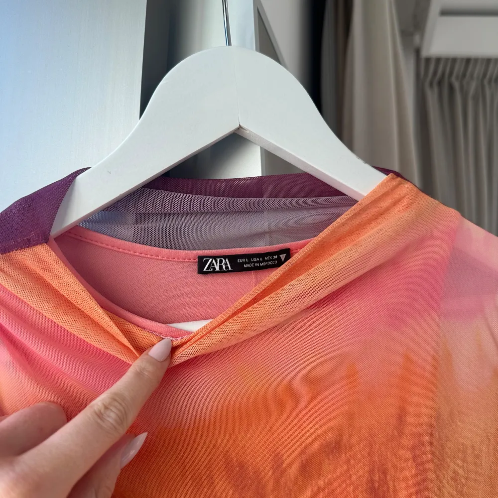 Säljer en färgglad långärmad topp från Zara med ett unikt mönster i orange, rosa och lila toner. Toppen har en rund hals och är tillverkad i ett lätt och bekvämt material. Perfekt för att liva upp garderoben! Passar som en storlek M. Puserot.