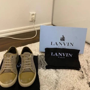 Lanvin sneakers i beige och grön - Snygga Lanvin sneakers i beige och grå med snörning. Skorna har en stilren design med en ljus sula och matchande skosnören. Perfekta för en avslappnad men grish look.