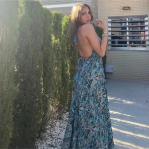 Mönstard långklänning  - Säljer en vacker långklänning med ett detaljerat mönster i blå och turkosa toner. Klänningen har en djup v-ringning och är ärmlös. Köpt på en marknad i Spanien och använd en gång❣️