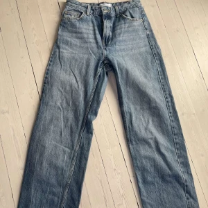 Blå jeansbyxor med baggy passform - Snygga blå low waist jeansbyxor med rak/bagy passform. Klassisk design med  fickor och en läderlapp med text baktill. Perfekta för en avslappnad stil.