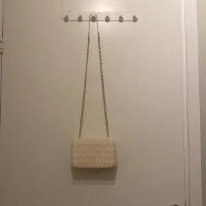 Off white axelrems väska från HM!  - Snygg off white/vanilla white väska från HM! Rymmer det man behöver när man ska ut på stan och är en perfekt touch till din outfit! Väskan har fått en lite fläck av kedjan på insidan! Syns att den är använd men är ändå i bra skick! Pris kan diskuteras vid snabbt köp och skorv för fler bilder! 🥰