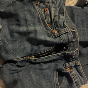 Blå jeans med hål - Säljer ett par jätte snygga, jätte lågmidjade jeans. Jag har sytt ner dom själv, och sytt dit en ny knapp. Jag har klippt ett hål upp på låret ganska högt upp. De ser inte lika runt ut i verkligheten som på bilden. Dom är i storlek XS men passar även på S. Säljer dom för att dom inte kommer till användning, hör av er vid intresse 😁