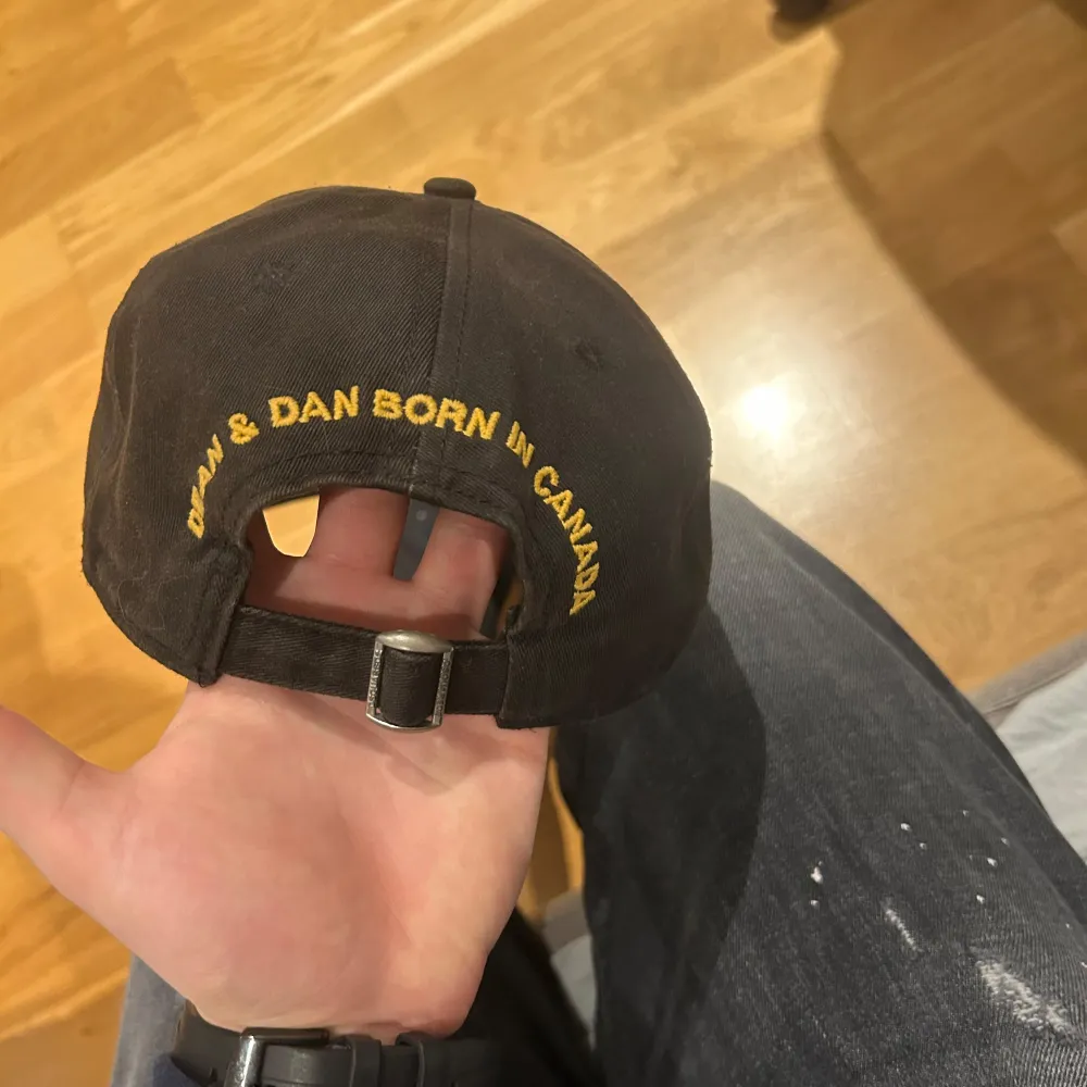 Snygg svart keps från Dsquared2 med broderad patch framtill. Patcher har en röd lönnlöv och text i vitt och gult. Justerbar rem baktill för perfekt passform. Perfekt för en casual look. Nypris: 2000 skick: 8,5/10 hör av dig vid eventuella frågor ☺️👍🏼kvitto finns . Asusteet.