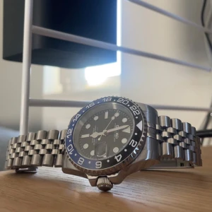 Seiko ”Batgirl” Mod - Säljer en Seiko klocka med en snygg blå och svart bezel. Klockan är helt ny och knappt använd. Diametern är 40 mm och kommer med extra länkbitar som enkelt kan justeras. Tveka inte att höra av dig vid frågor.