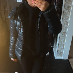 Blå dunjacka - Säljer en snygg svart dunjacka med dragkedja. Jackan har en pufferdesign och långa ärmar, perfekt för kyligare dagar. Den är både stilren och praktisk.